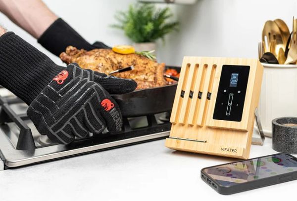 Wireless meat thermometer and grilling tools on a modern kitchen counter for precise outdoor cooking.