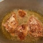 Digital thermometer cooking meat in hot oil; food thermometer for precise cooking.